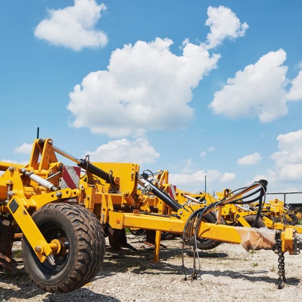 Close up of seeder attached to tractor in field. Agricultural machinery for spring works sowing, seeding